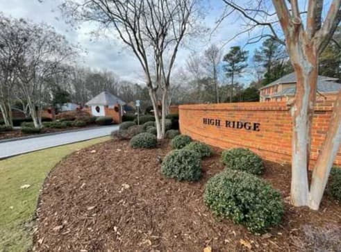 Clean brick community entrance sign and landscaped grounds after pressure washing