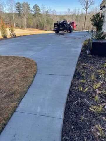 Freshly cleaned concrete driveway with professional pressure washing equipment on site