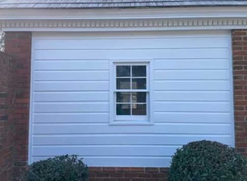 White lap siding and red brick exterior cleaned with soft washing